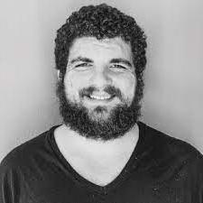 Black and white photo of smiling man with curly hair and a beard